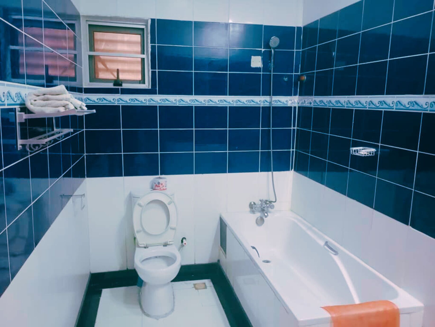 A bathroom with a toilet, bathtub, and a window.