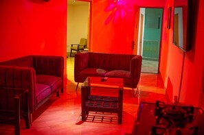 A room with two dark-colored sofas, a small wooden table, and a red wall. - Spring Park Yaad Hotel (Lagos)