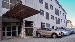 Un edificio con fachada de tejas, un acceso cubierto y varios coches aparcados.