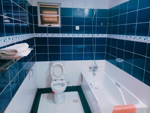 A bathroom with a toilet, bathtub, and a towel rack. - Spring Park Yaad Hotel (Lagos)