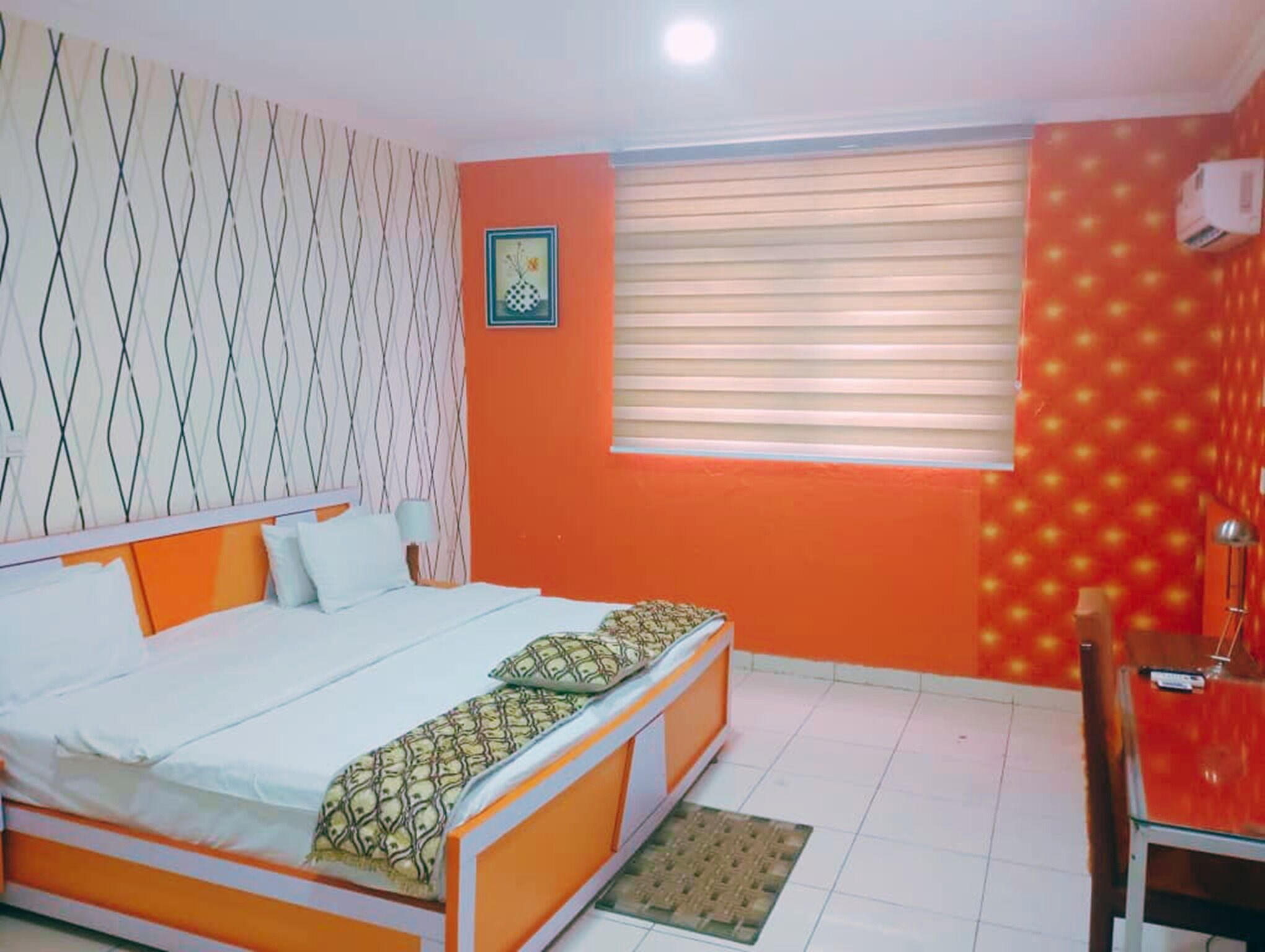 A room with a bed, a window with blinds, a picture on the wall, and a chair.
