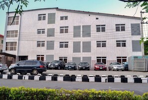 A multi-story building with a tiled facade, several windows with shutters, and a parking area with various cars. - Spring Park Yaad Hotel (Lagos)