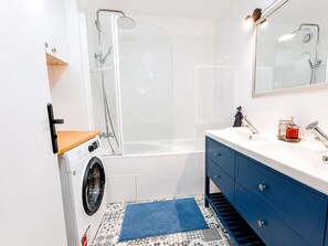 Casa de banho compacta com máquina de lavar, cabine de duche, banheira e toucador com espelho.