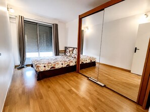 Quarto com cama, guarda-roupa e janela com cortinas.