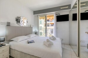 Ein Hotelzimmer mit Bett, Nachttisch, Fernseher und Fenster mit Blick auf Gebäude.