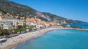 Un pueblo costero con playa, edificios y una montaña al fondo.