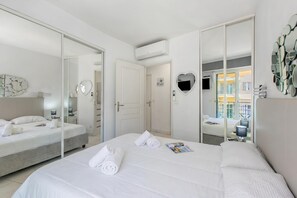 Ein Hotelzimmer mit einem Bett, einem Nachttisch, einem Spiegel und einer Tür zu einem weiteren Raum.