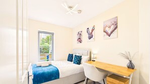 Een slaapkamer met een bed, een bureau, een stoel en kunst aan de muur.