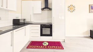 Een moderne keuken met witte kastjes, een zwarte oven, een magnetron en een broodrooster.