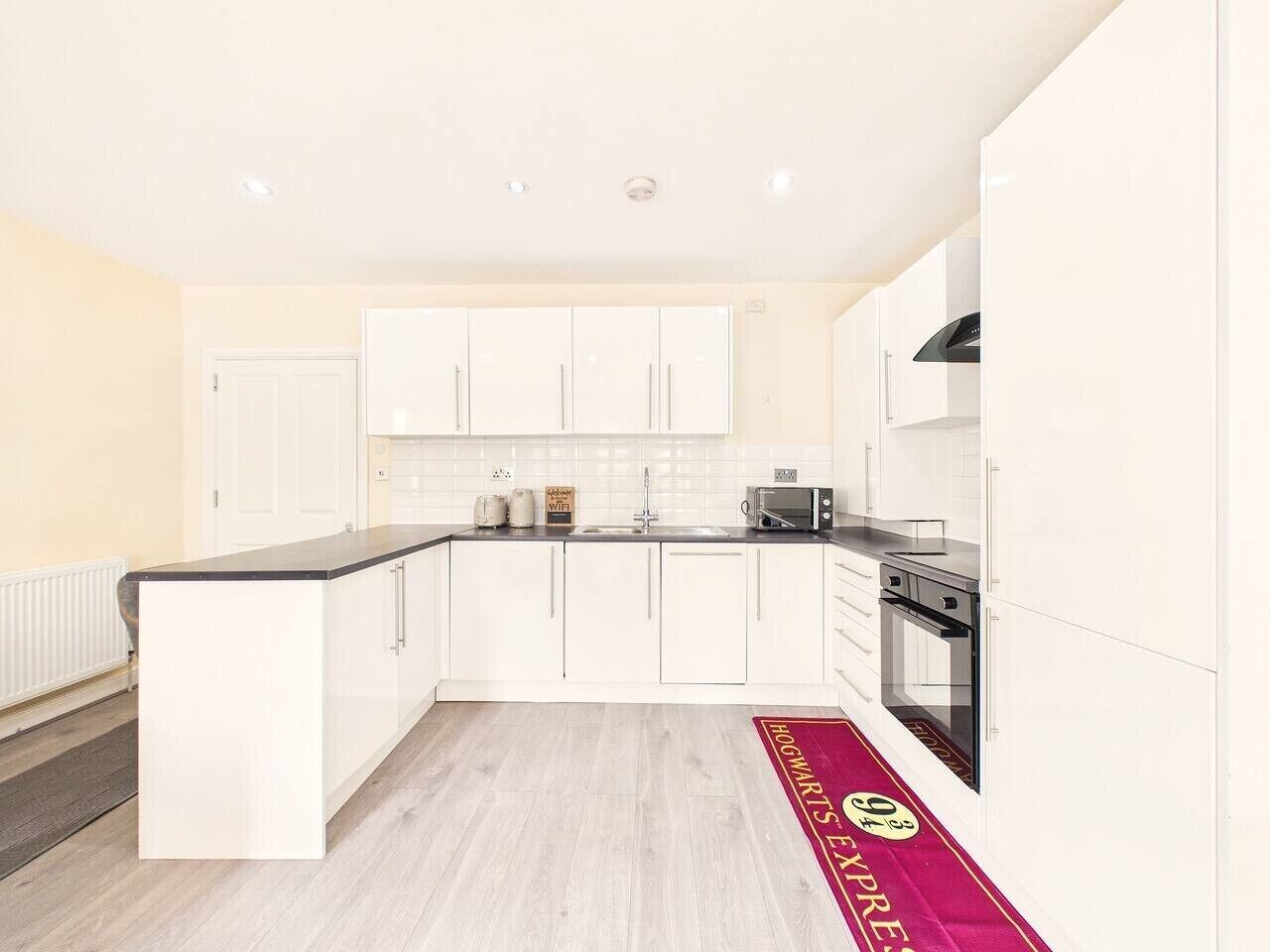 Una cocina moderna con armarios blancos, una isla central, un microondas y un horno.