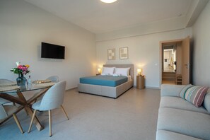 Un dormitorio moderno con cama, mesitas de noche, televisor y un área de comedor con sillas y mesa.