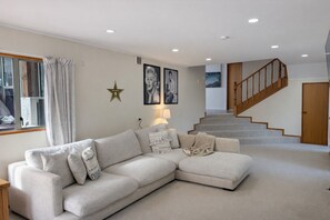 A living room with a sectional sofa, a staircase, and a star decoration on the wall.