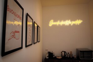 Ein gerahmtes Kunstwerk an der Wand, ein Neonzeichen und eine Küchenarbeitsplatte mit Geräten.