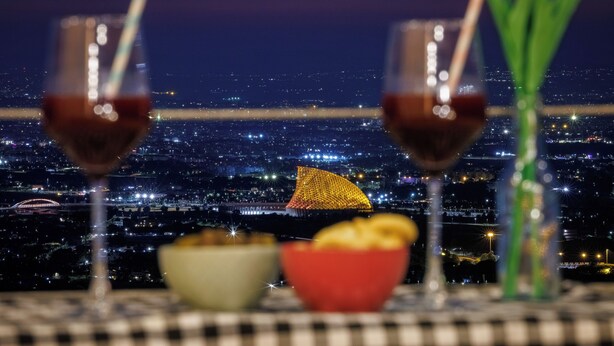 Une table avec deux verres de vin rouge, un bol de chips et une plante verte.