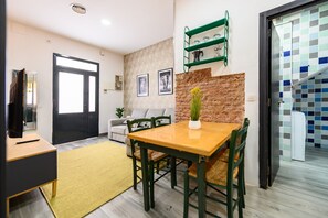Ein Wohnzimmer mit einer Couch, einem Esstisch und einer Küchenzeile mit Fliesenrückwand.