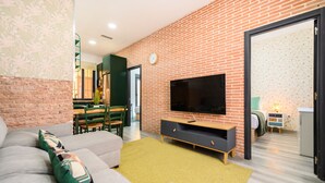 Ein modernes Wohnzimmer mit einer Couch, einem Fernseher und einer Ziegelwand.