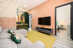 Ein modernes Wohnzimmer mit einer Couch, einem Fernseher und einer Ziegelwand.