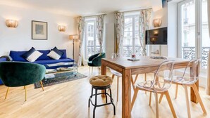 Ein modernes Wohnzimmer mit einem blauen Sofa, einem Holzesstzimmer und klaren Stühlen.