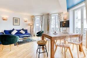 Ein modernes Wohnzimmer mit einem blauen Sofa, einem Holzesstzimmer und klaren Stühlen.