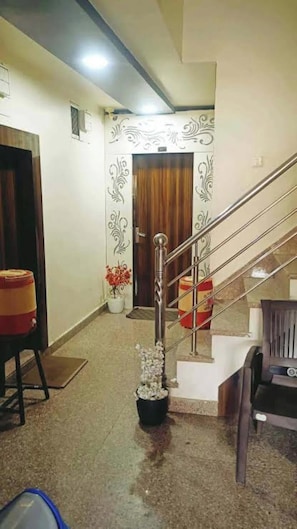 A hallway with a staircase, a door, and a potted plant. - Hotel Sheeba Ajmer (Ajmer)