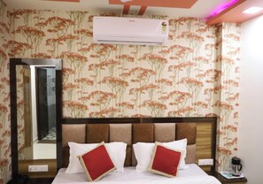 Een hotelkamer met een bed, een spiegel, een airconditioner en bloemenbehang.