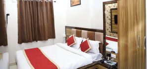 Een hotelkamer met een bed, een houten hoofdeinde, een spiegel, een kledingkast en een rood-witte plaid.
