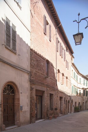 Una stretta via fiancheggiata da edifici storici, un lampione e cielo sereno.