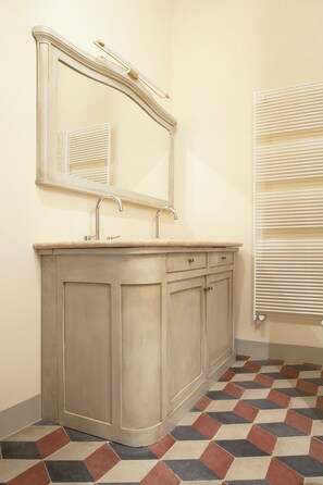 Een badkamer met een wastafel, spiegel en radiator.