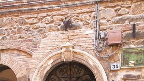 A stone building with a wooden door, a metal archway, and a number '35' sign. - Wp Relais Apartment Argante (Montalcino)