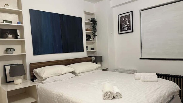 Een netjes ingerichte hotelkamer met een bed, nachtkastjes, een bureau en een groot raam.