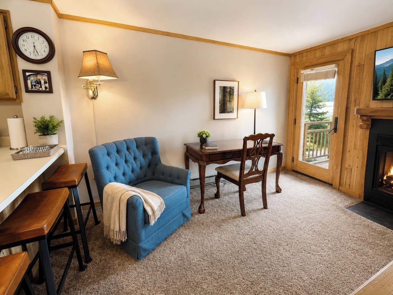 A cozy room with a blue sofa, wooden dining table, chairs, a lamp, a clock, and a fireplace.