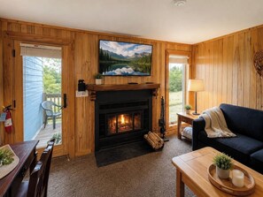 Ein gemütliches Wohnzimmer mit Kamin, einem darüber montierten Fernseher und einer Couch.
