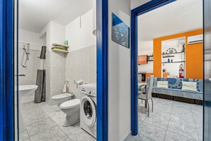 Un bany modern amb rentadora, vàter i dutxa.