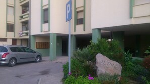 Ein Gebäude mit Parkschild, einem davor parkenden Auto und einem Felsen mit der Aufschrift 'IL PINO'.