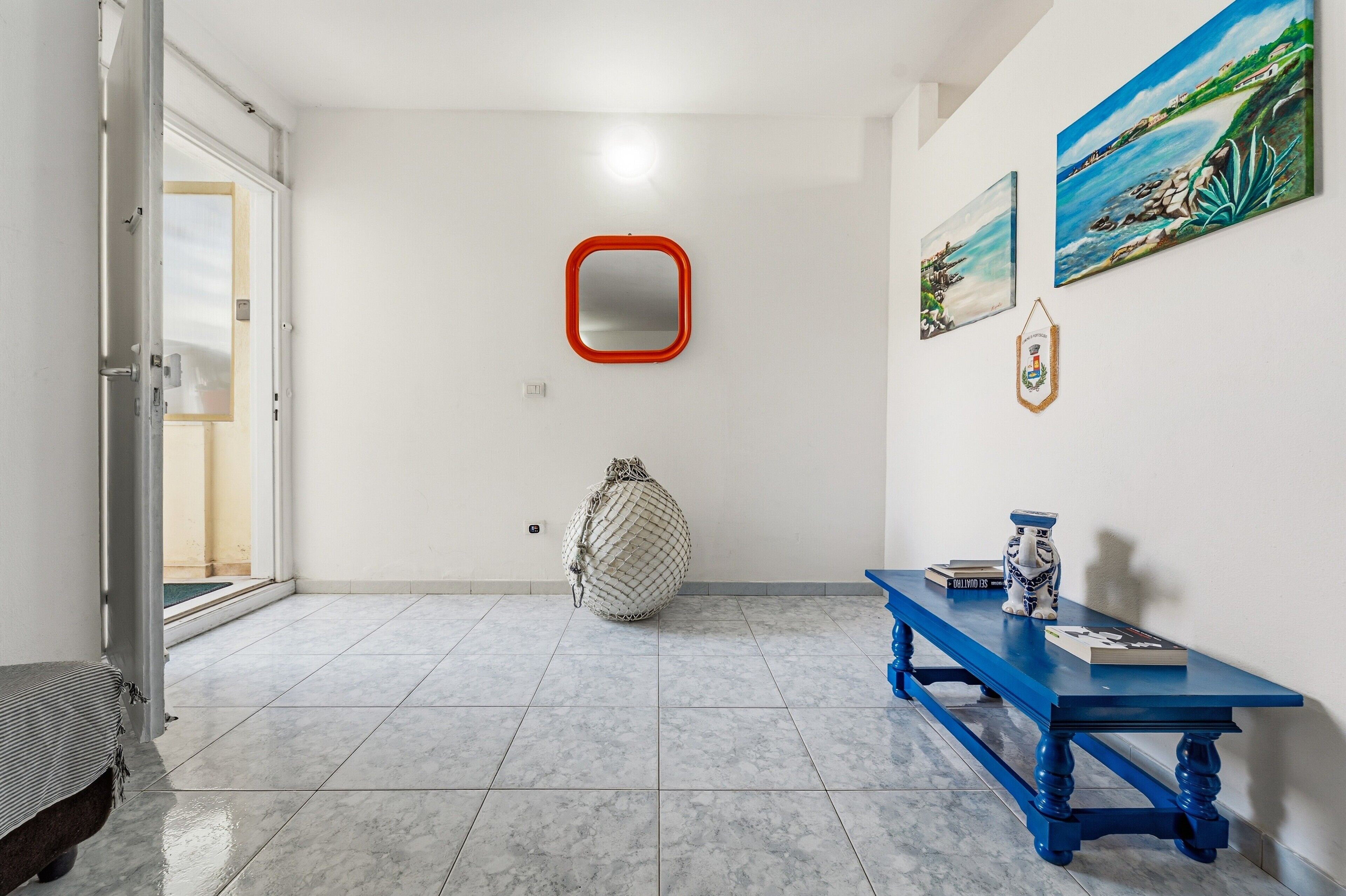 A hallway with a blue table, a mirror, and artwork on the wall.