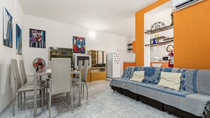 Ein Wohnzimmer mit einer Couch, einem Esstisch, Stühlen und Bildern an den Wänden.