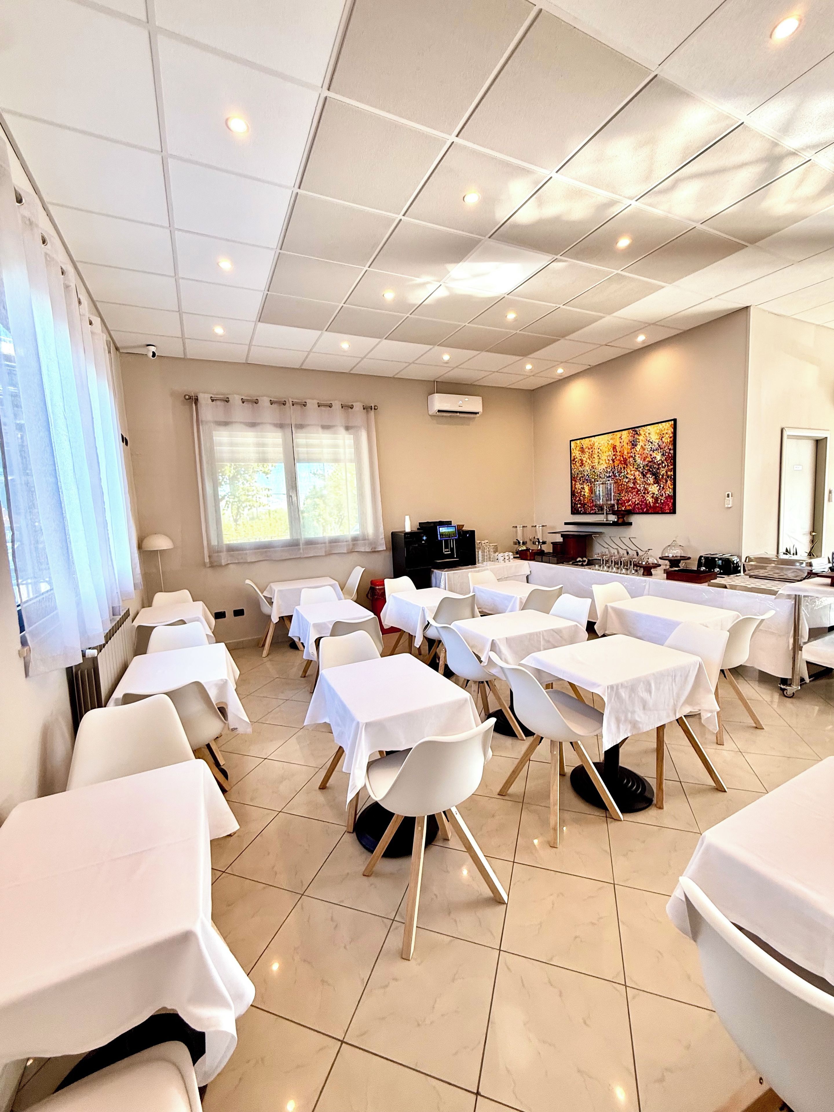 A conference room with tables and chairs, a projector, and a painting on the wall.