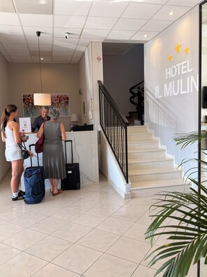 Zona de recepción de un hotel con una escalera que sube a los pisos superiores.