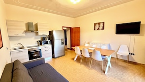 Un espacio habitable compacto con kitchenette, comedor, sofá y televisor de pantalla plana.