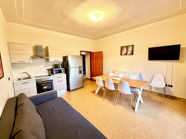 A compact living space with a kitchenette, a dining area, a sofa, and a flat-screen TV. - HOTEL IL MULINO (Casalgrande)