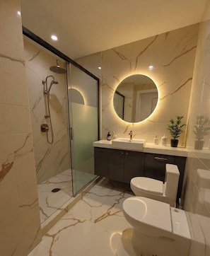 A modern bathroom with a glass-enclosed shower, a round mirror, a white sink, and a toilet. - HOTEL IL MULINO (Casalgrande)
