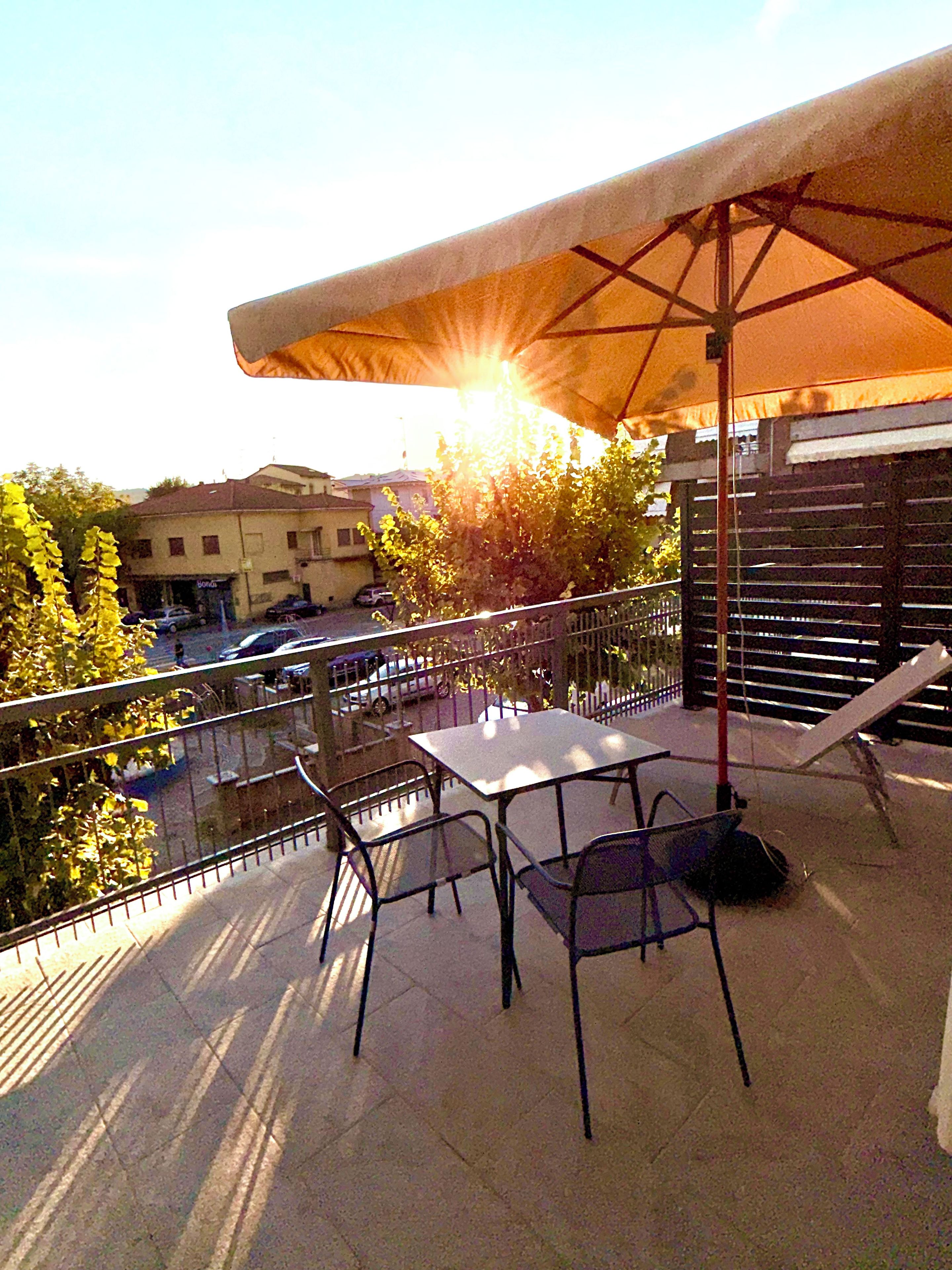 Una terrazza esterna con tavolo e sedie, un ombrellone e vista sui dintorni.