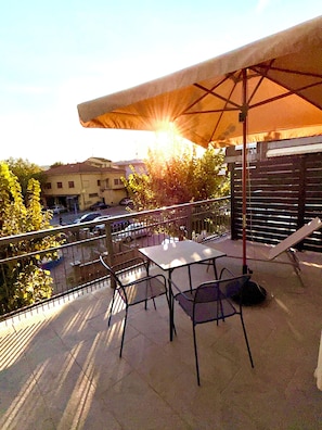 Eine Außenpatio mit Tisch und Stühlen, einem Sonnenschirm und Blick auf die Umgebung.