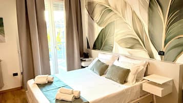 A hotel room with a large bed, a nightstand, a lamp, and a view of the outdoors.