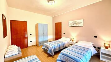 A bedroom with two beds, a wardrobe, a mirror, and a ceiling light.