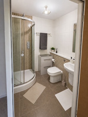 A bathroom with a glass-enclosed shower, a toilet, a sink, and a mirror. - Stylish 2-Bed 2-Bath Apartment with Parking, Lift & Balcony - London & Airports (Croydon)
