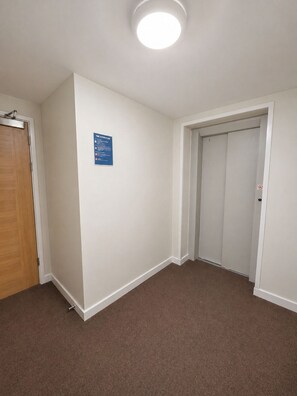 A room with a brown carpet, white walls, a wooden door, and a closed closet door. - Stylish 2-Bed 2-Bath Apartment with Parking, Lift & Balcony - London & Airports (Croydon)