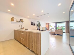 Eine moderne Küche mit Holzschränken, einer Spüle und einem Essbereich mit einer Couch und einem Tisch.