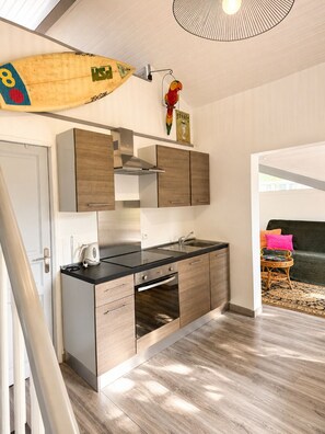 Une cuisine moderne avec des meubles en bois, un plan de travail noir et une hotte en acier inoxydable.