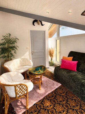 Un salon avec un canapé, des fauteuils, une petite table, une porte et une plante.